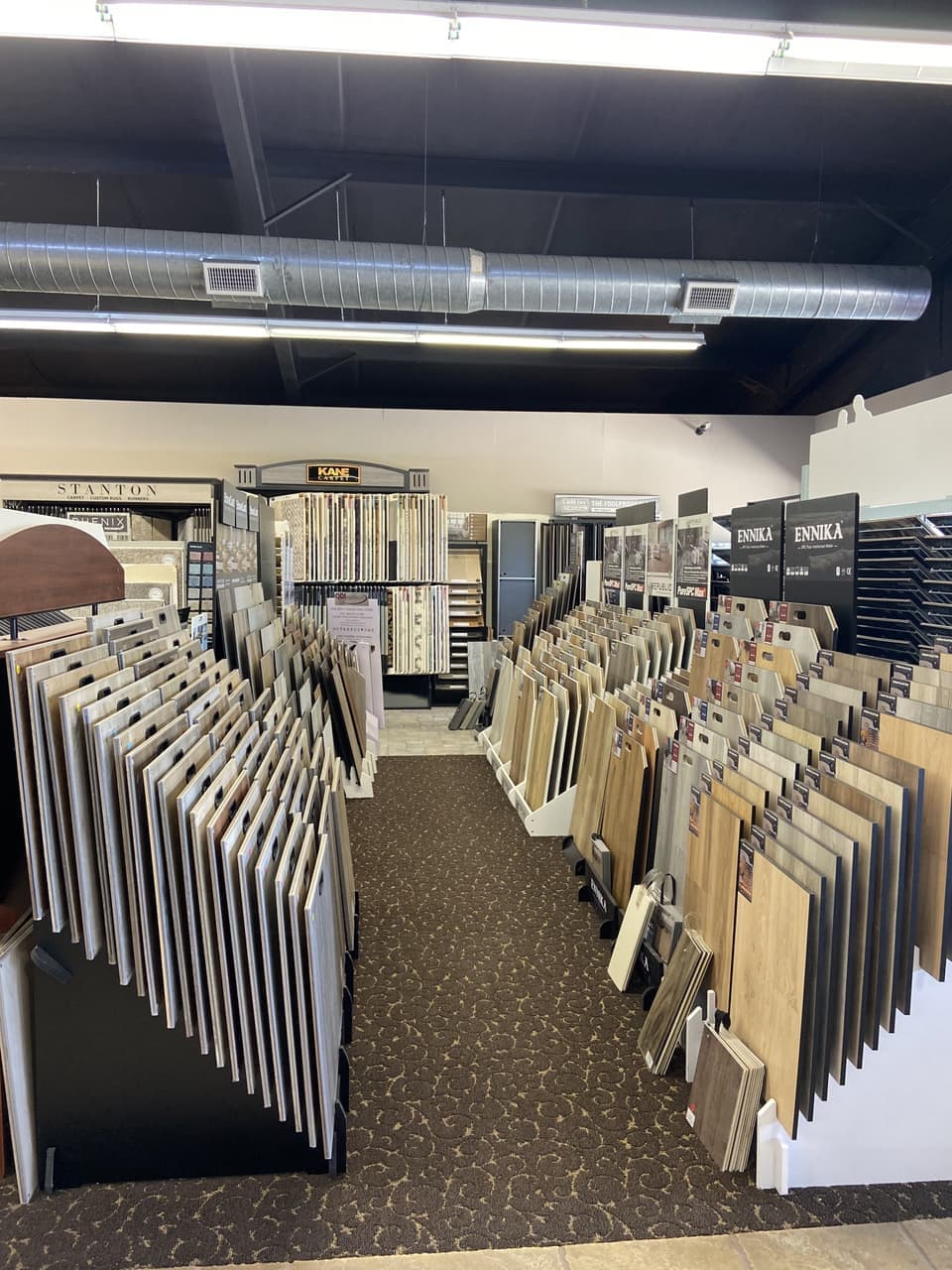 Tile, carpet, and waterproof flooring showroom aisle featuring Stanton, Kane Carpet, QDIsurfaces, and Ennika