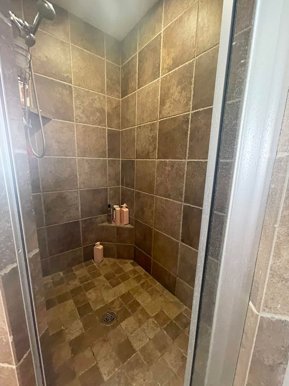 Stone-look ceramic tile shower stall with corner shelf in a Cresson, TX bathroom